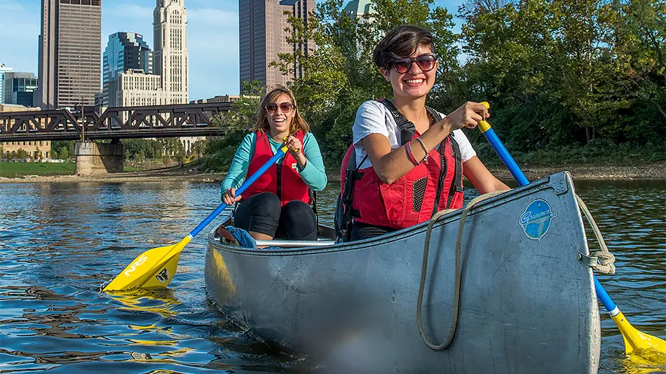 two female students canoeing down the Olentangy River on campus