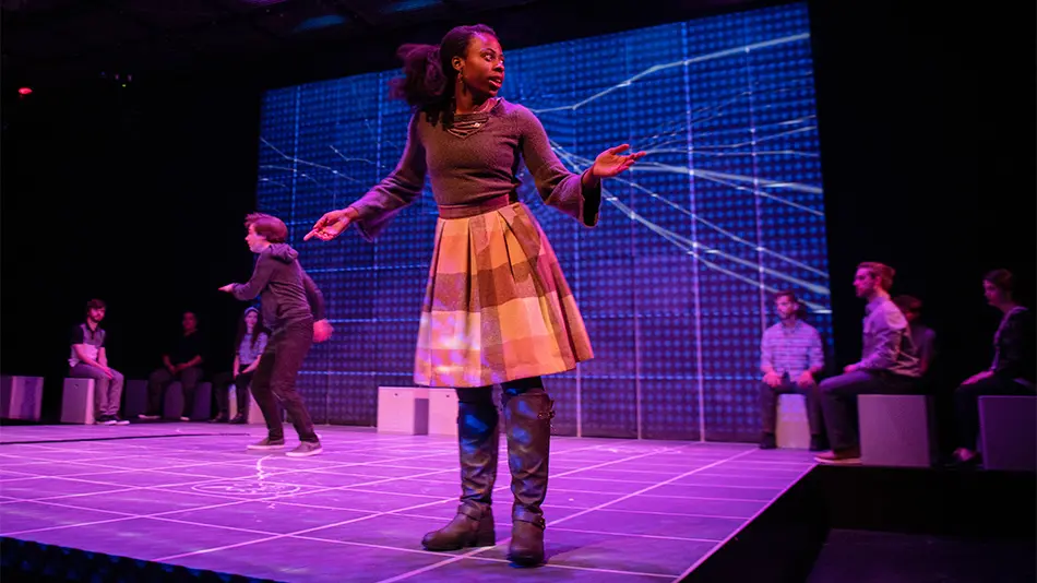 Graduate student Lillian Brown acting in a play on stage with purple lights