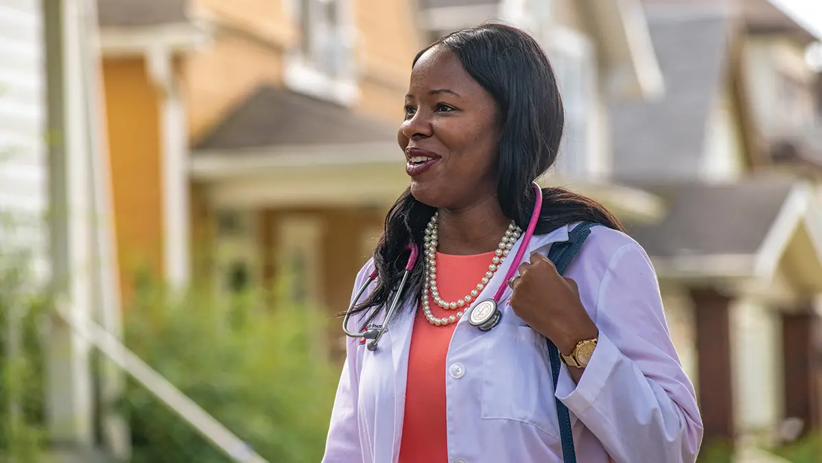 Dr. Olayiwola, a Black women with long hair in a white coat and a stethoscope around her neck, Dr. J. Nwando Olayiwola