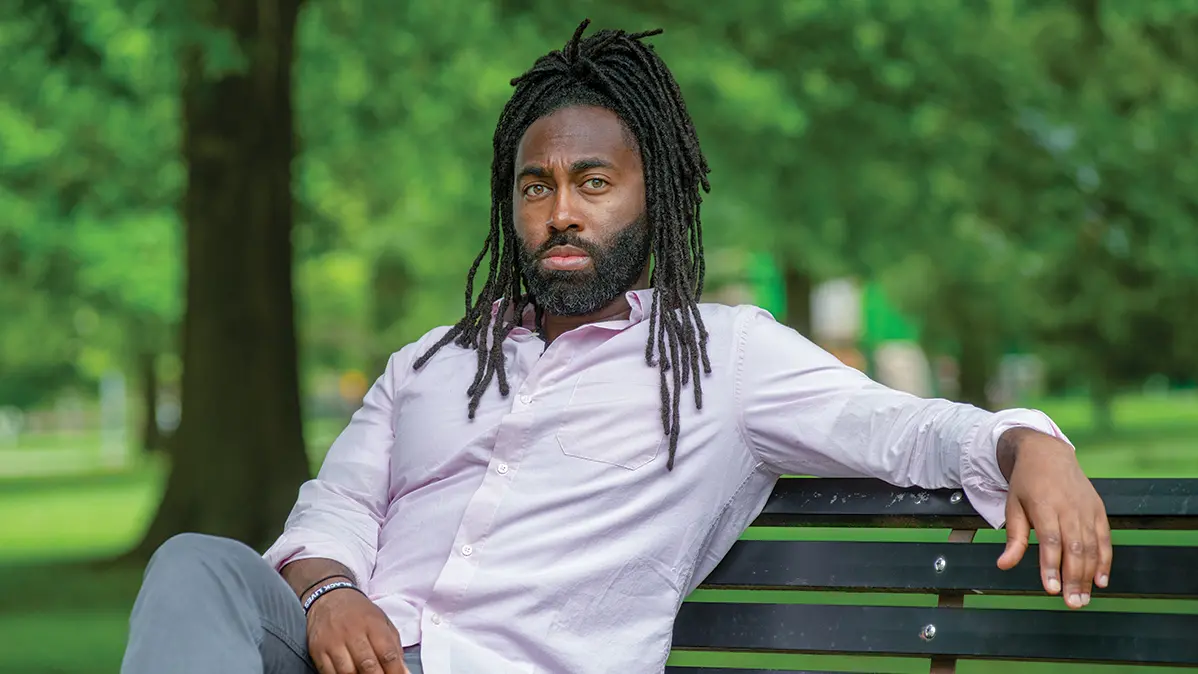 Headshot of Jared Thorne, a Black man sitting on a bench with long hair and a beard