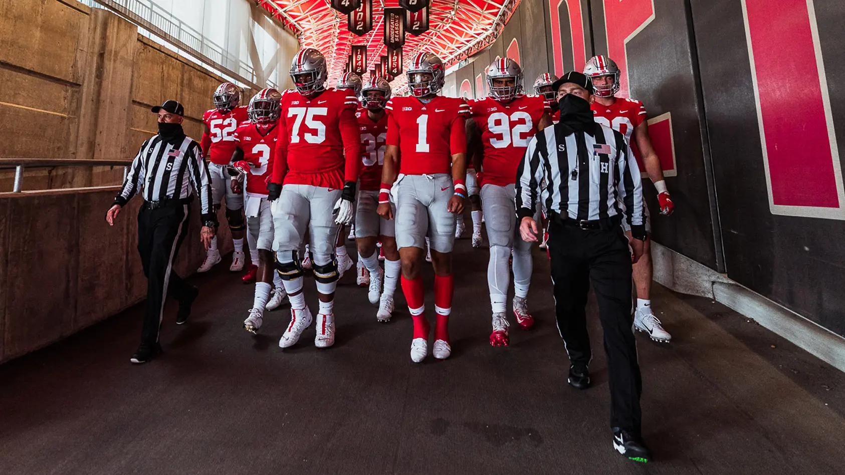 Ohio State players in uniform walk down tunnel led by refereees