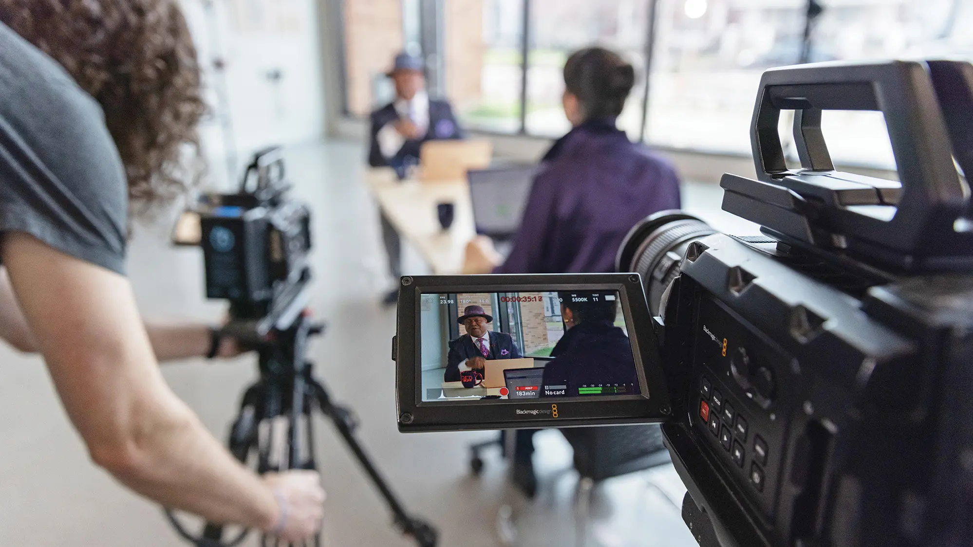 A camera operator captures an interview between a man and a woman