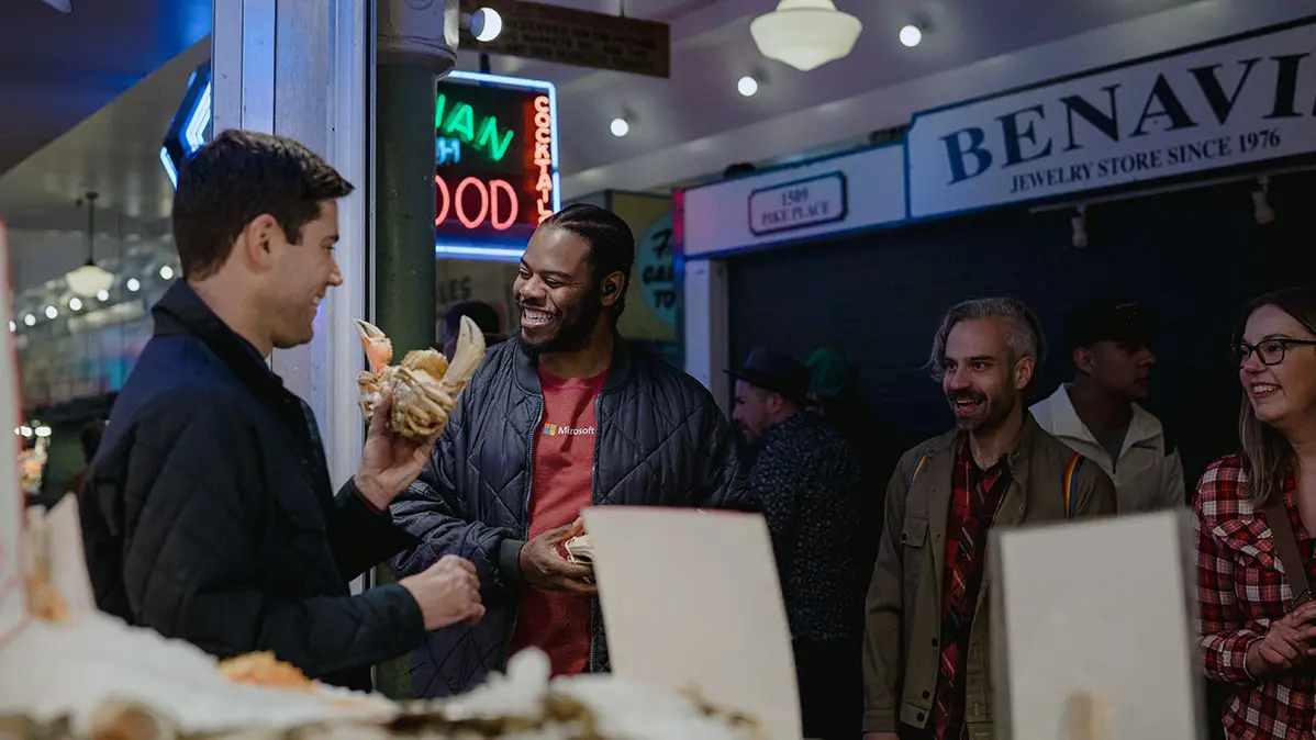 A man shows three friends a crab as they laugh along.