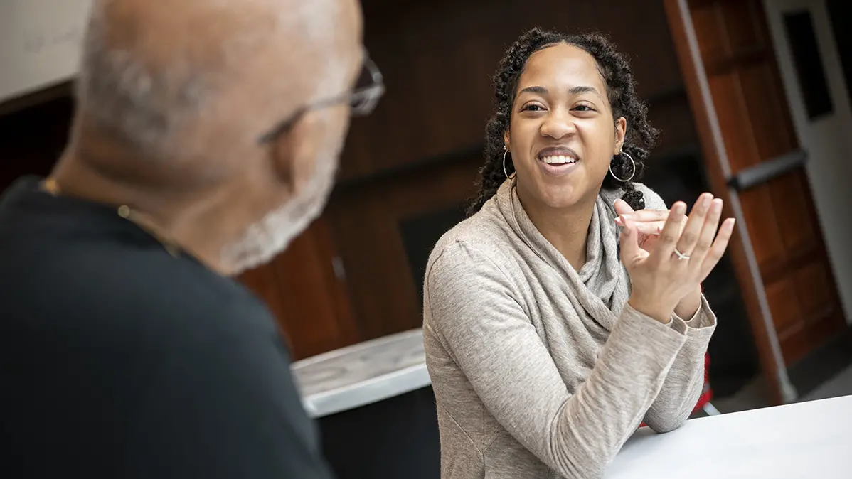 A young Black woman smiles at the fellow scientist who funded her scholarship