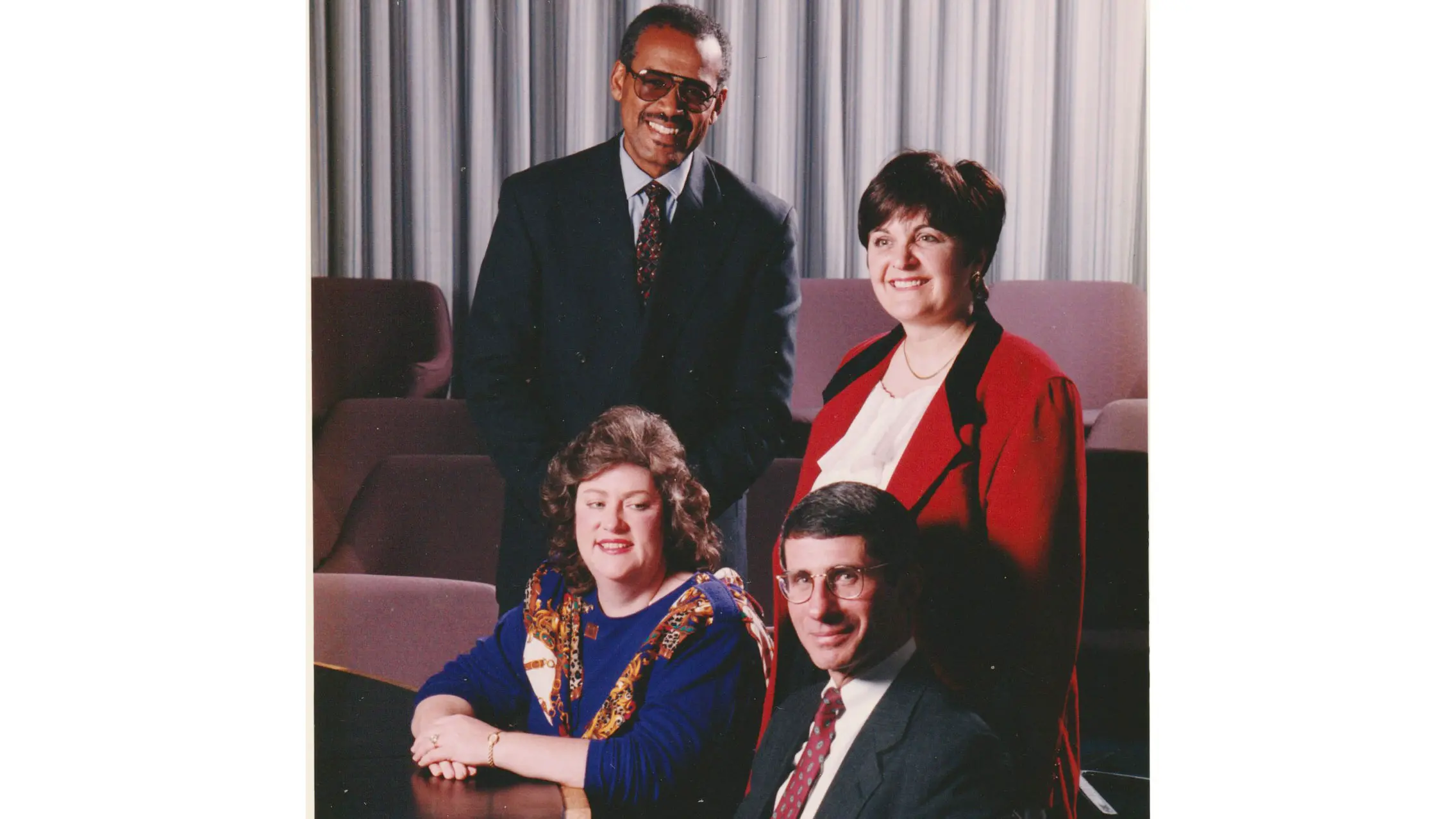 Dressed in a suit, Johnson poses for a photo with three other people, including a well-known face from these Covid-19 times, Dr. Anthony Fauci. All are smiling.