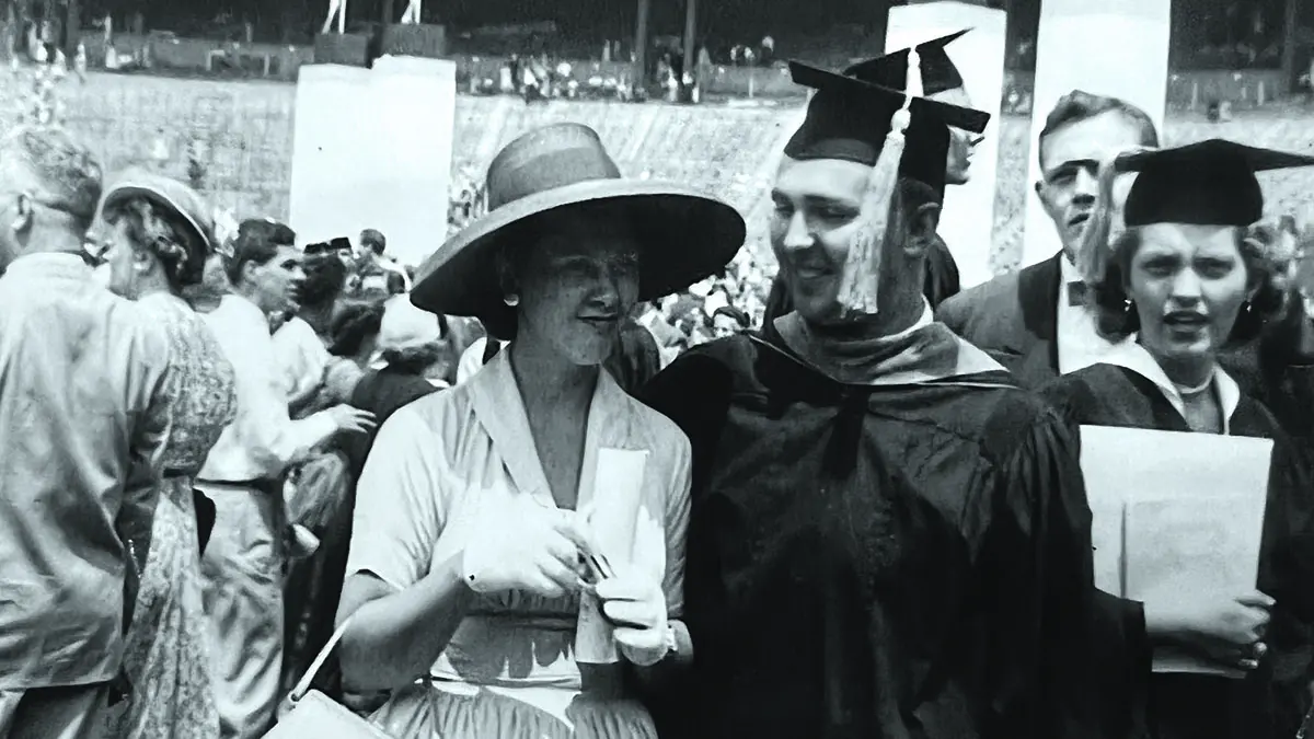In an old black-and-white photograph, a young man in cap and gown smiles at his wife, who’s wearing a hat, gloves and dress. They’re inside Ohio Stadium and many more Buckeyes are behind them.