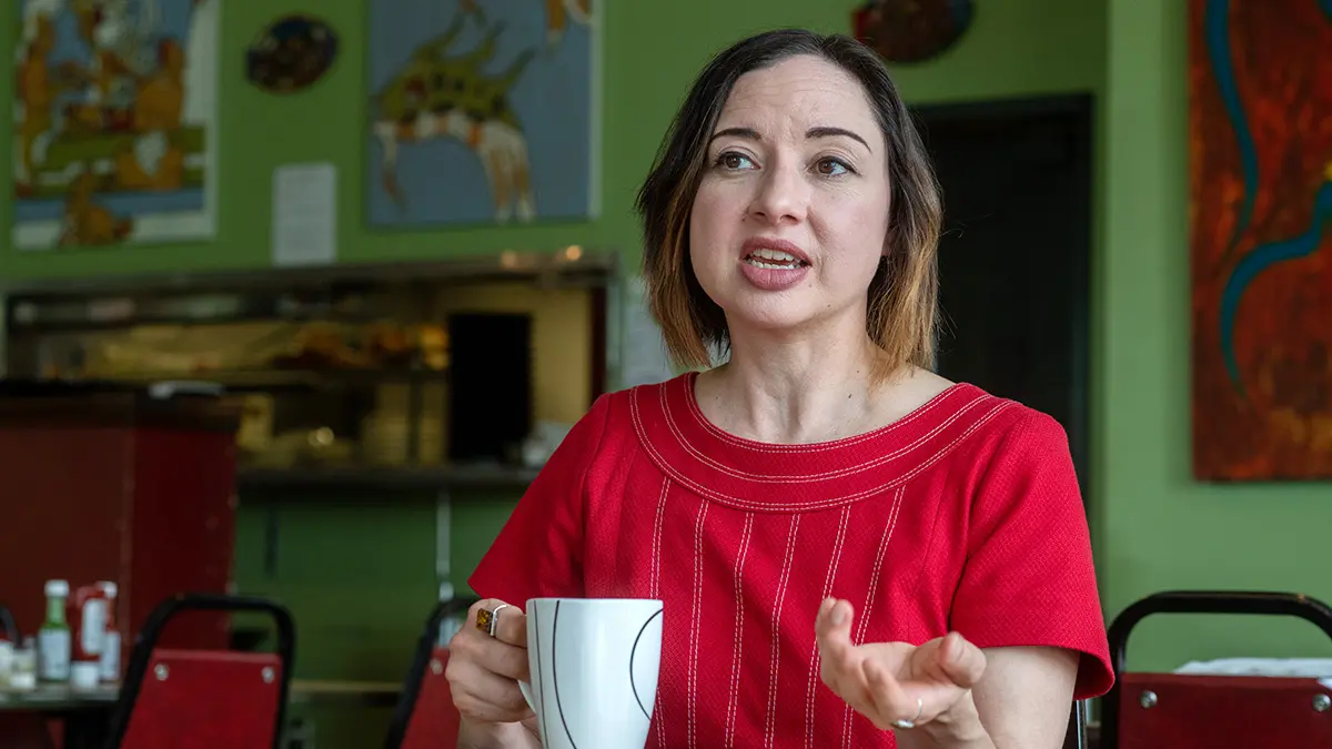 Portrait of Paloma Martinez-Cruz in a red shirt having coffee or tea