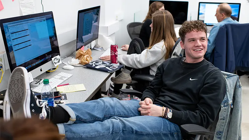 Man sitting in front of a computer with his feet up on a desk