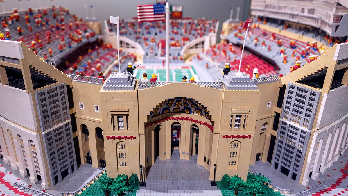 A view of the Lego stadium shows the main rotunda entrance and, beyond, out-of-focus field, stands and Lego people as spectators.