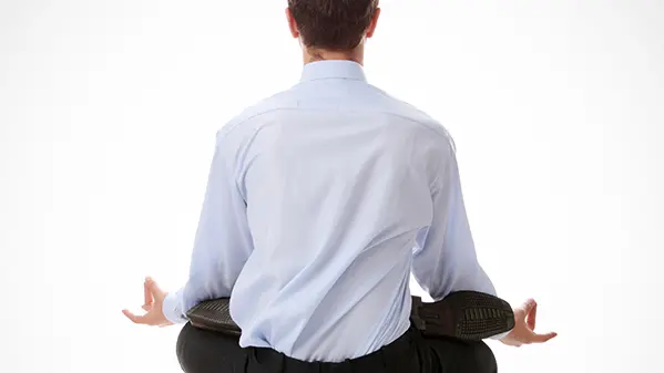 A man with his back to the viewer sits in a seated yoga position