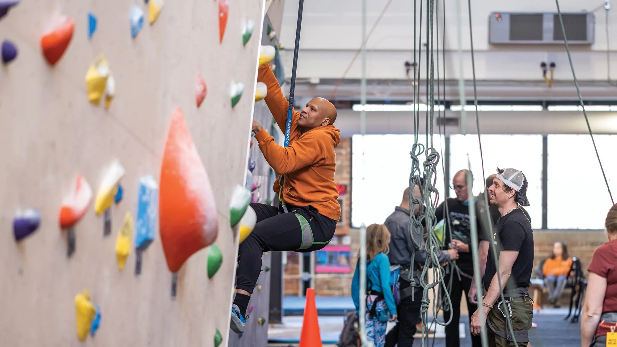 Wearing sweats and connected to a safety line, Ryan Shazier looks for the next handhold to continue ascending a climbing wall.