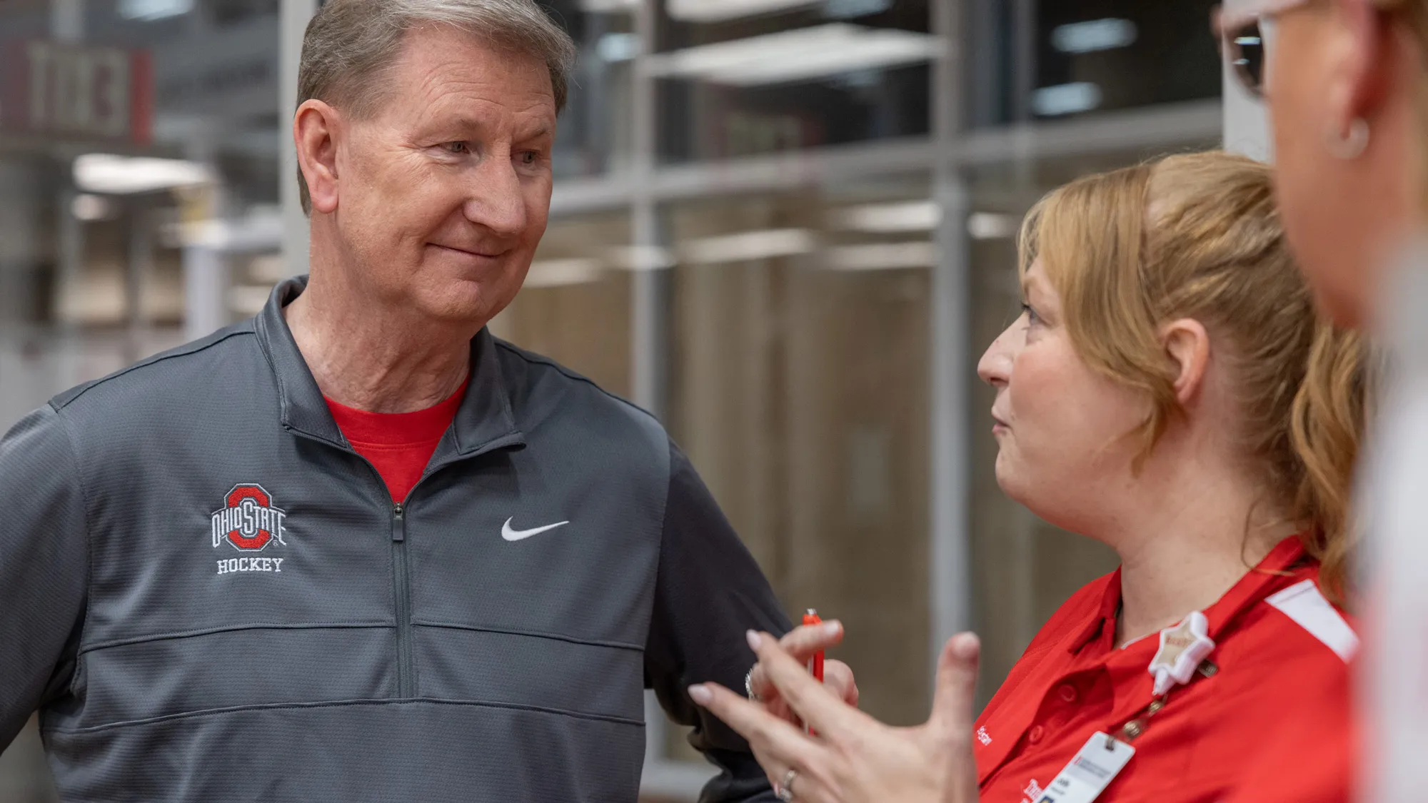 Ohio State President Walter “Ted” Carter Jr. listens intently to a university staff member. As she gestures and speaks, he meets her eyes and his expression shows his interest in what she is saying.