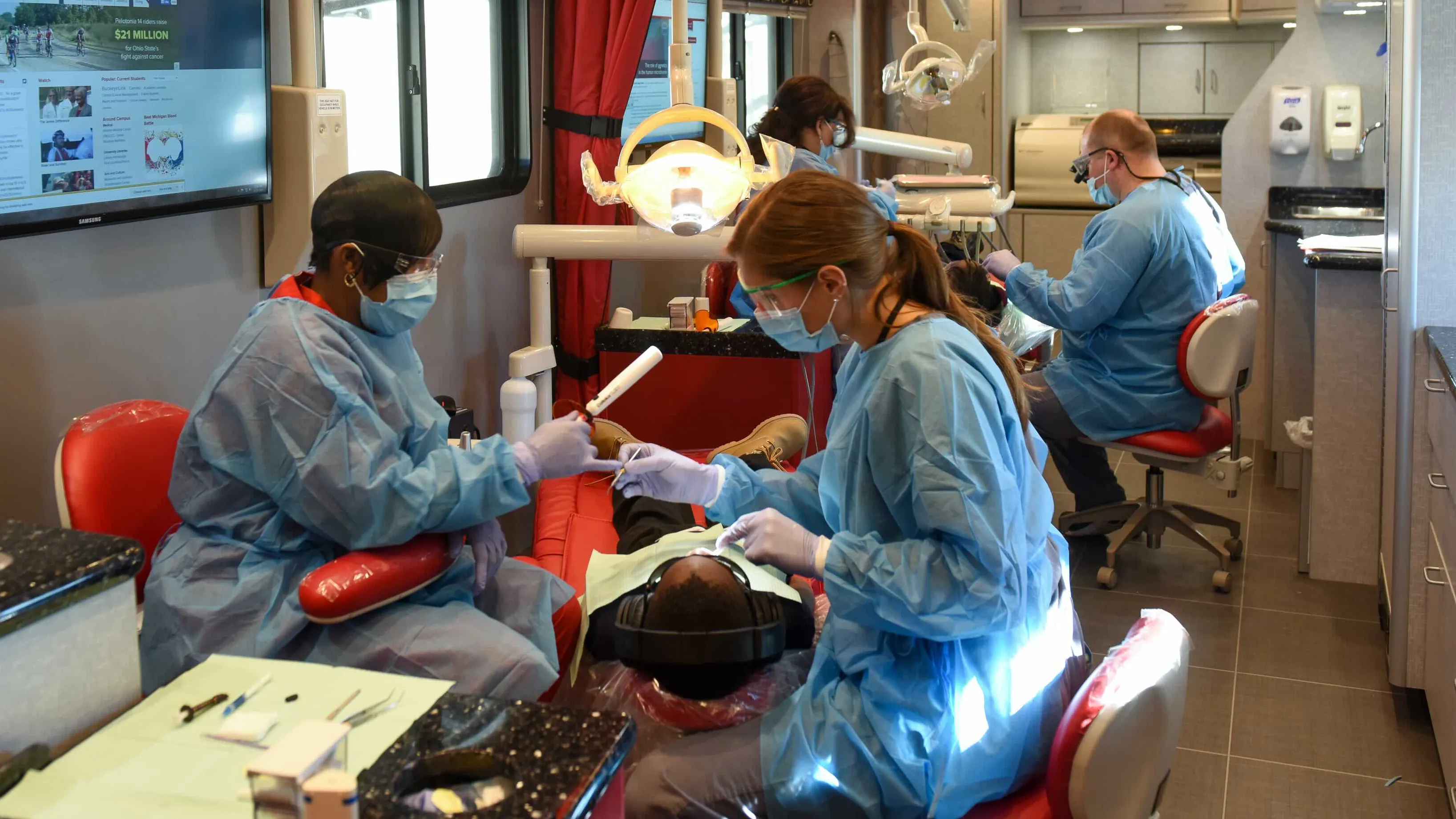 Dentists and student dentists work inside a mobile exam room