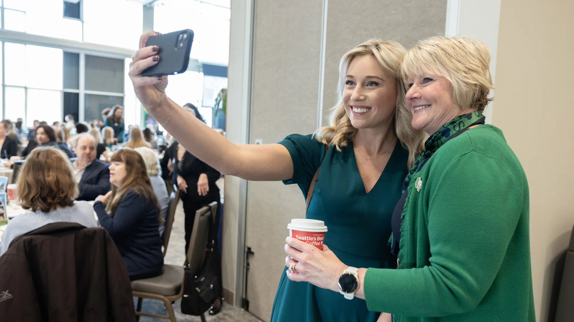 Wharton poses for a cellphone selfie with another woman, who has long blond hair the same shade as Wharton’s and even wears a similarly colored dress to Wharton’s kelly green and navy outfit. Besides their difference in age, they look strikingly similar as they smile. 