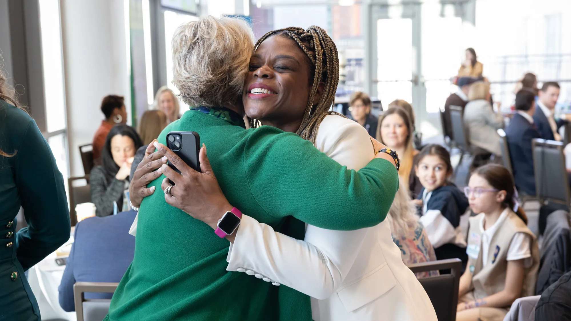 At the Girl Scouts conference, Wharton hugs a black woman wearing a white suit jacket. Wharton’s face doesn’t appear in the photo, but the other woman seems genuinely pleased. Her eyes are closed and her smile is wide. 