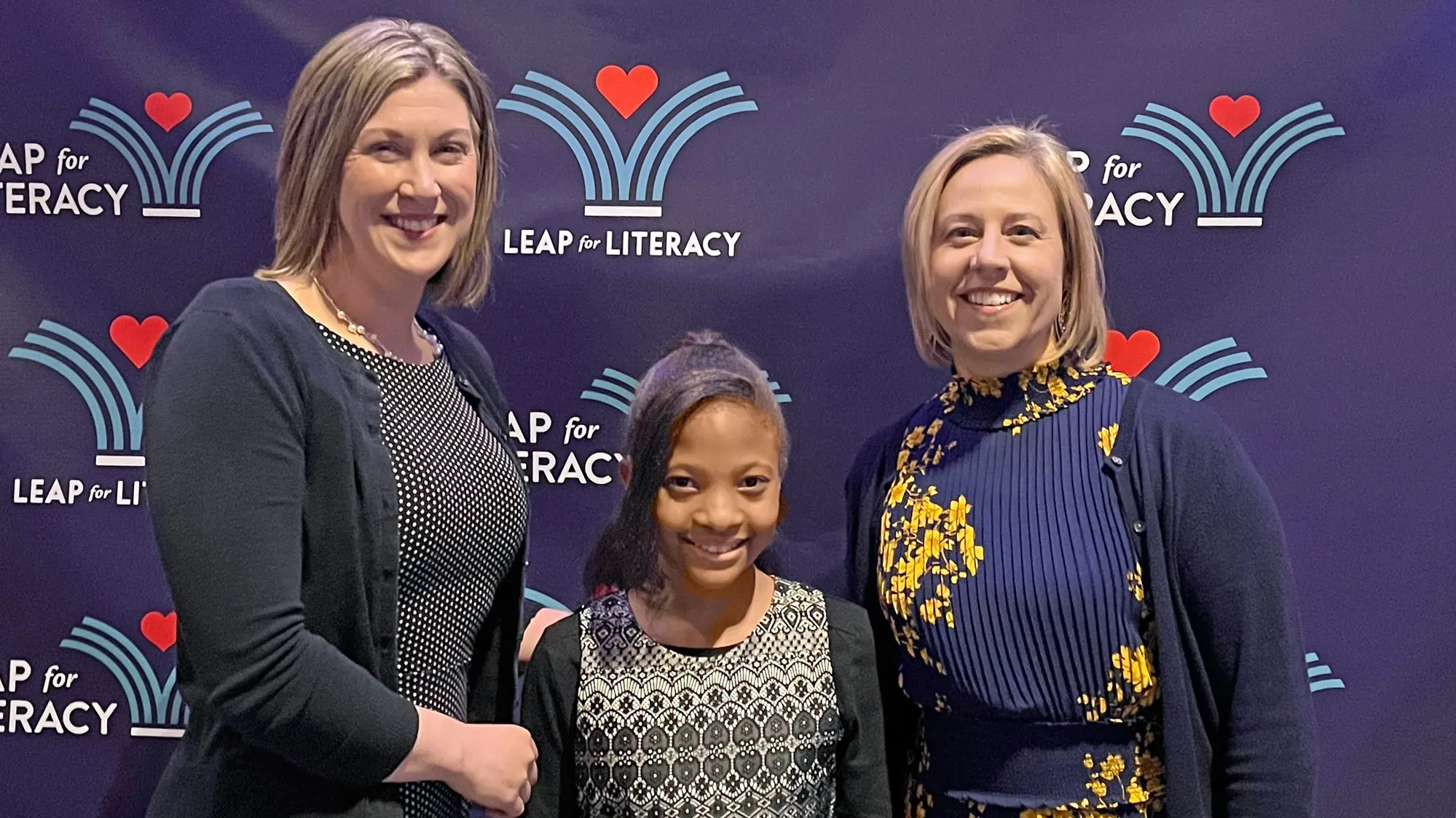 Amanda Waters Fields, left, proudly poses with one of her middle school students and another teacher as they attend an event for Leap for Literacy, a nonprofit that encourages reading by giving free books to children.