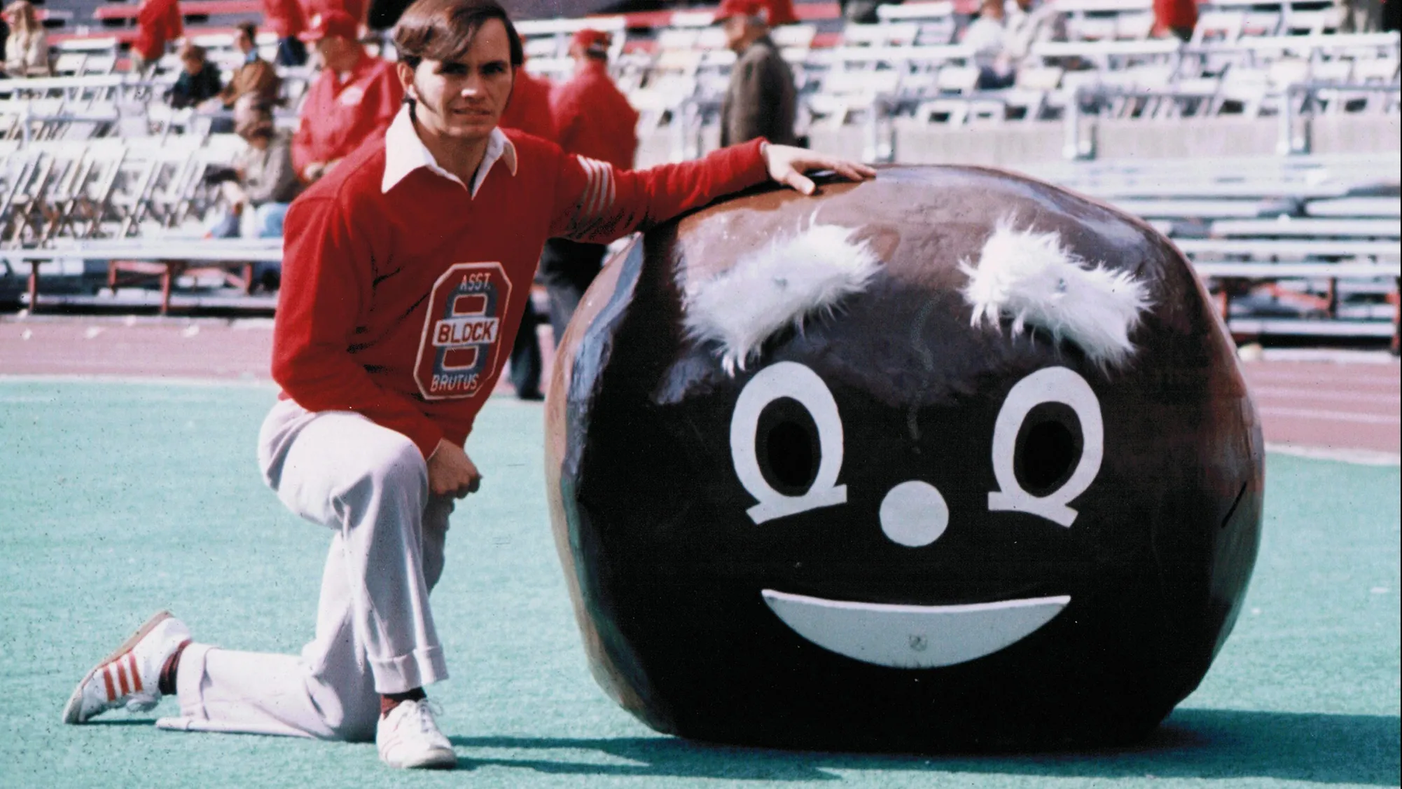 In his college days, Lester Cline was a built young man with chestnut colored hair. He poses on a sunny day inside Ohio Stadium, kneeling on one leg and posing with his hand on the giant Brutus Buckeye head he would have worn. It’s probably almost 4 feet wide and must have been heavy. It has a smiley face on it with bushy eyebrows.