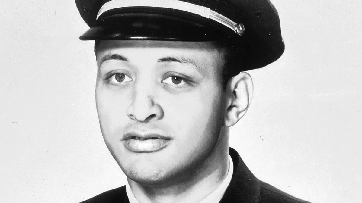 David Harris poses for an American Airlines headshot in a suit and narrow tie and pilot’s hat. He is a Black man and his expression says he is serious yet open or trustworthy—like someone you’d trust to fly your plane.