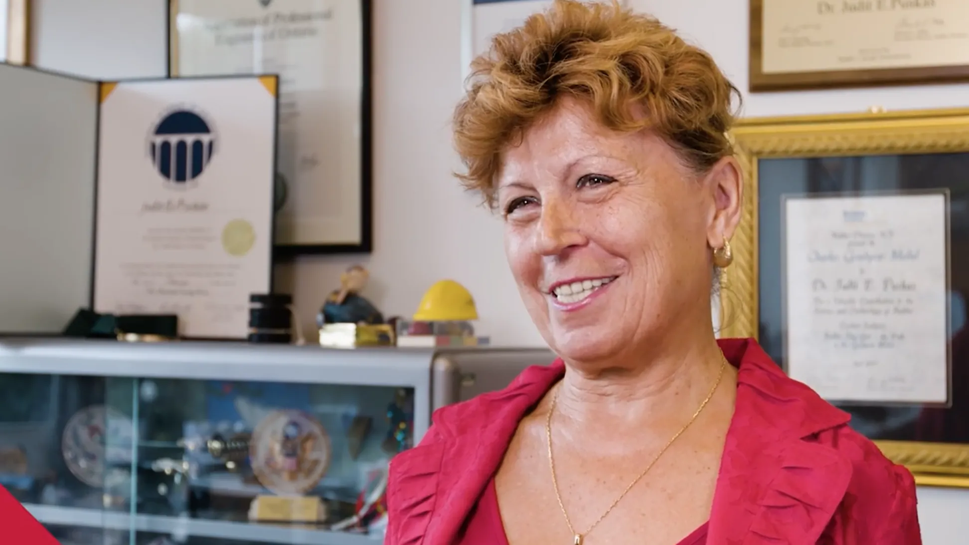 Judit Puskas smiles as she talks about her work in her office. Awards line the wall behind her.