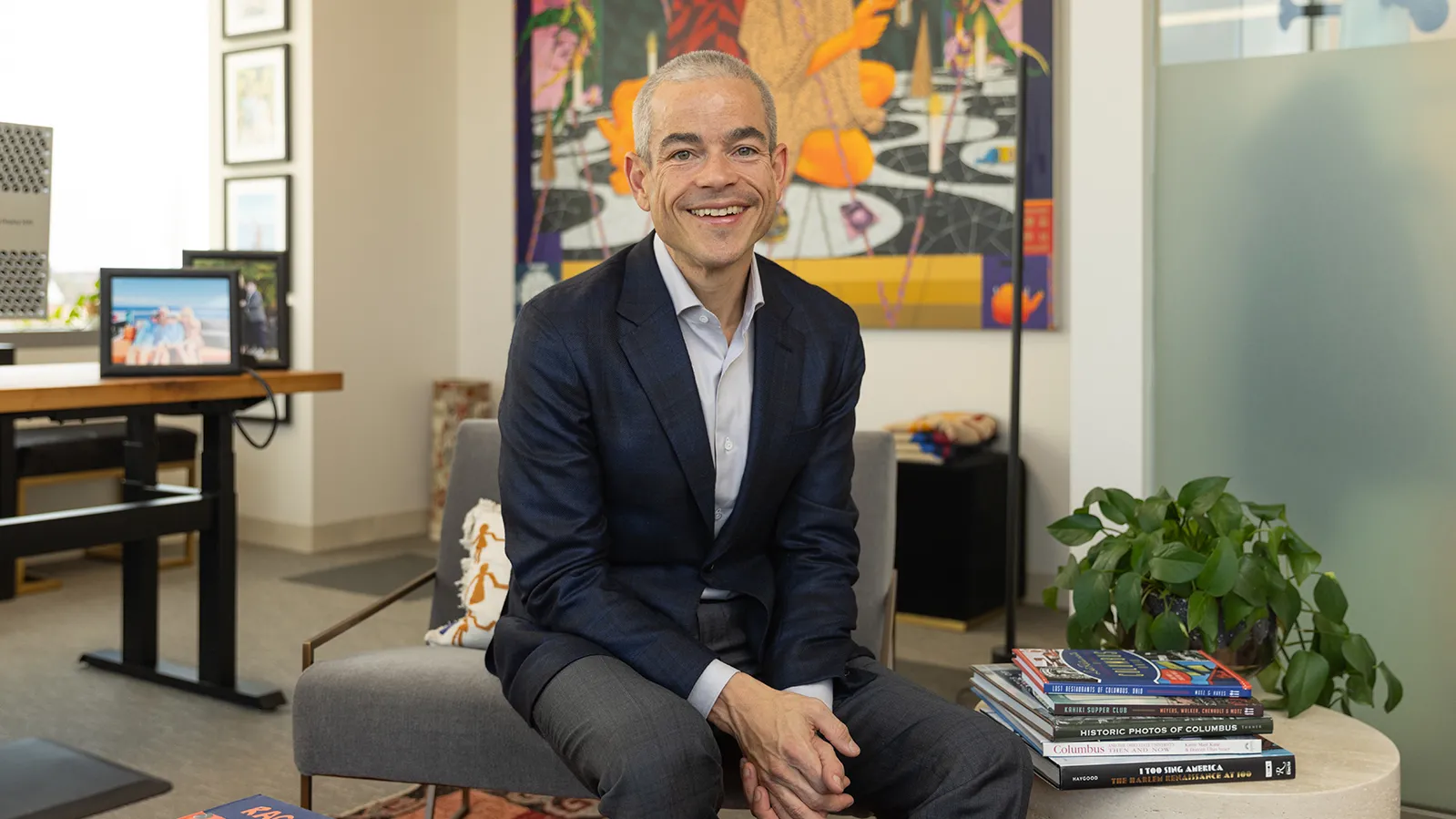 Matt Scantland smiles as he poses for a portrait in his office. He's a thin, white, middle age man with close cropped hair wearing a sportcoat. His smile is genuine.