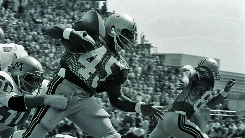 Archie Griffin tries to evade defenseman while carrying the football in a black and white photo from a game