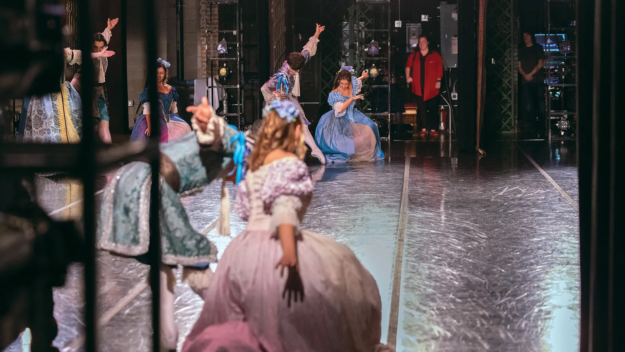 Ballet dancers practice on stage while in the wings opposite of where the photographer stood, an Ohio State athletic trainer watches how comfortably they move.