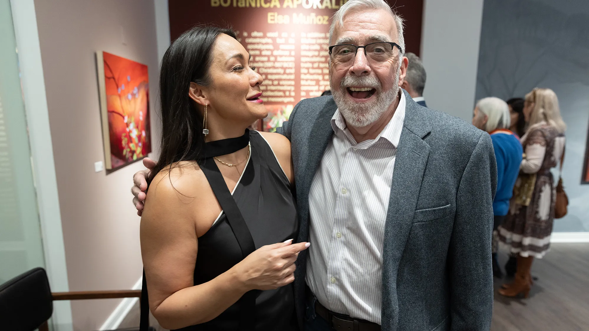 Michelle Brandt and Duff Lindsay laugh as they stand with arms around each other. Their amusement feels genuine and comfortable.