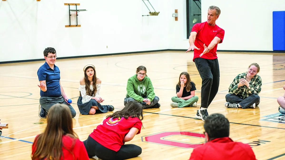 In a gymnasium, teens sit in a circle around Kevin McClatchy, an assistant professor who is pretending to curse the girl in front of him. They're enacting a Shakespeare scene, and she gets him back next.