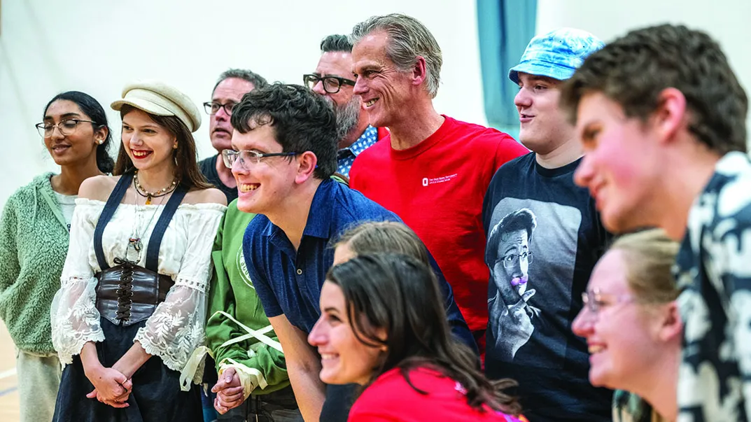 associate professor Kevin McClatchy grins as he poses with teens and college students who took and helped with a Shakespeare in Autism session. Everyone has big smiles.
