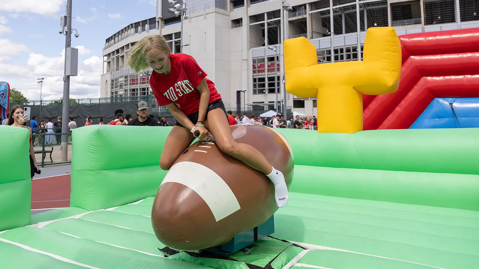 During welcome week, a first year student rides a football like a bucking bronco.