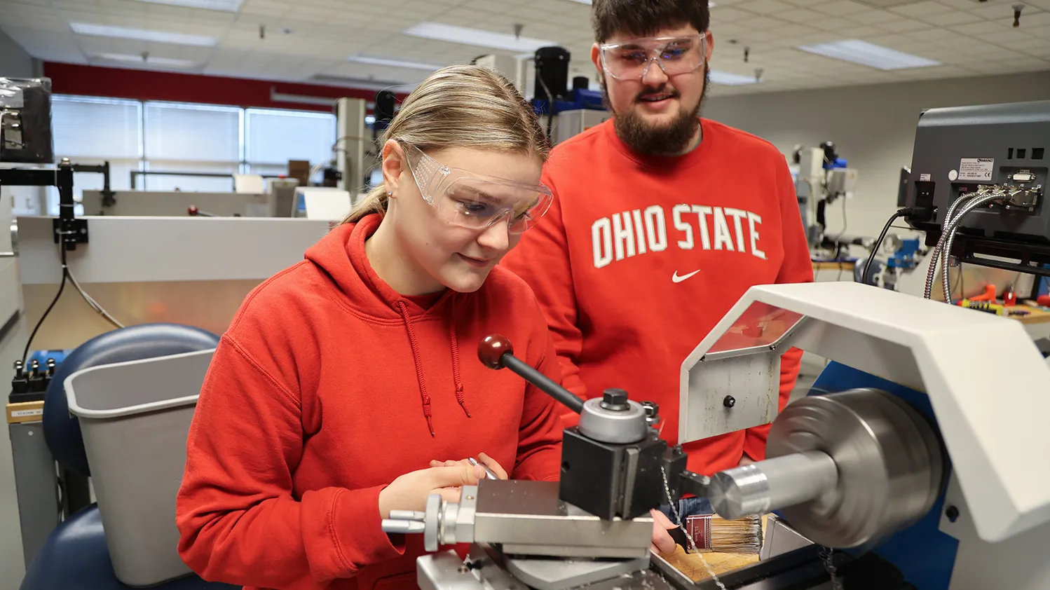 Two Ohio State students work in a manufacturing classroom. A lave is in front of them. Both are white; one is a young blonde woman and the other is a man with dark hair and beard.