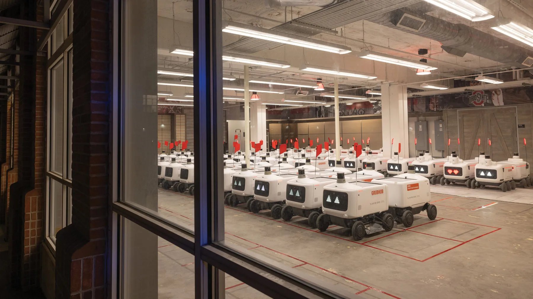 Dozens of food delivery robots are lines up in their home base, a facility located on the bottom floor of a parking garage near the Shoe.