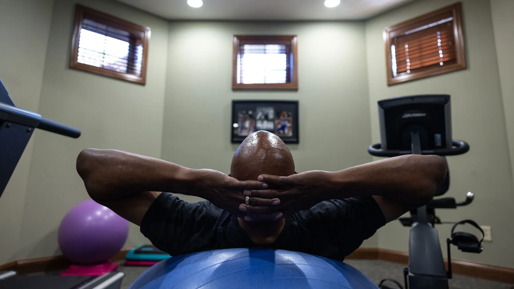 Kellogg lies back on an exercise ball with hands clasped behind his head in his home workout room, as if getting ready to do crunches.