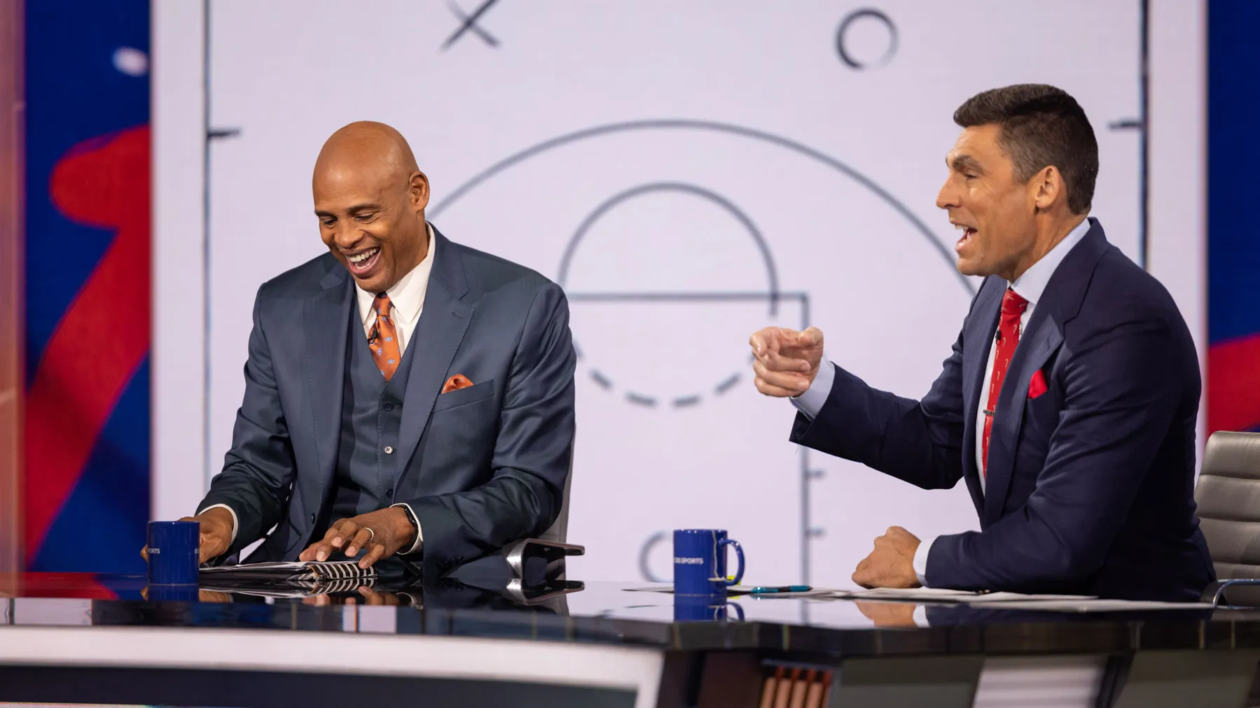 Dressed in suits and back in the TV studio, Kellogg and Wally Szczerbiak sit behind a broadcast desk and talk while cameras roll.
