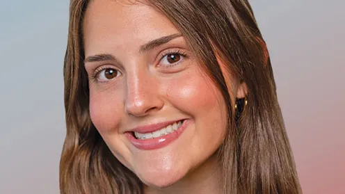 A young woman with long hair smiles as she looks directly into the camera