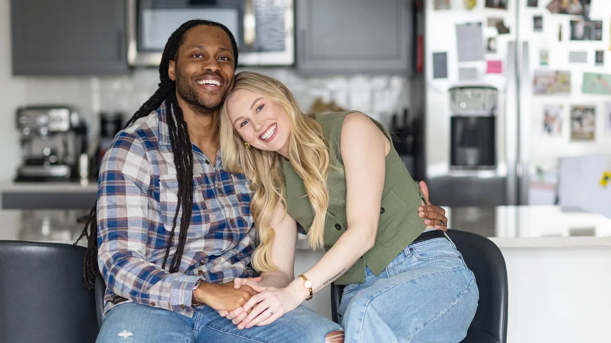 Victor St John and Christine Hamilton pose for a photo in their home. They appear happy as she leans her head on his shoulder.