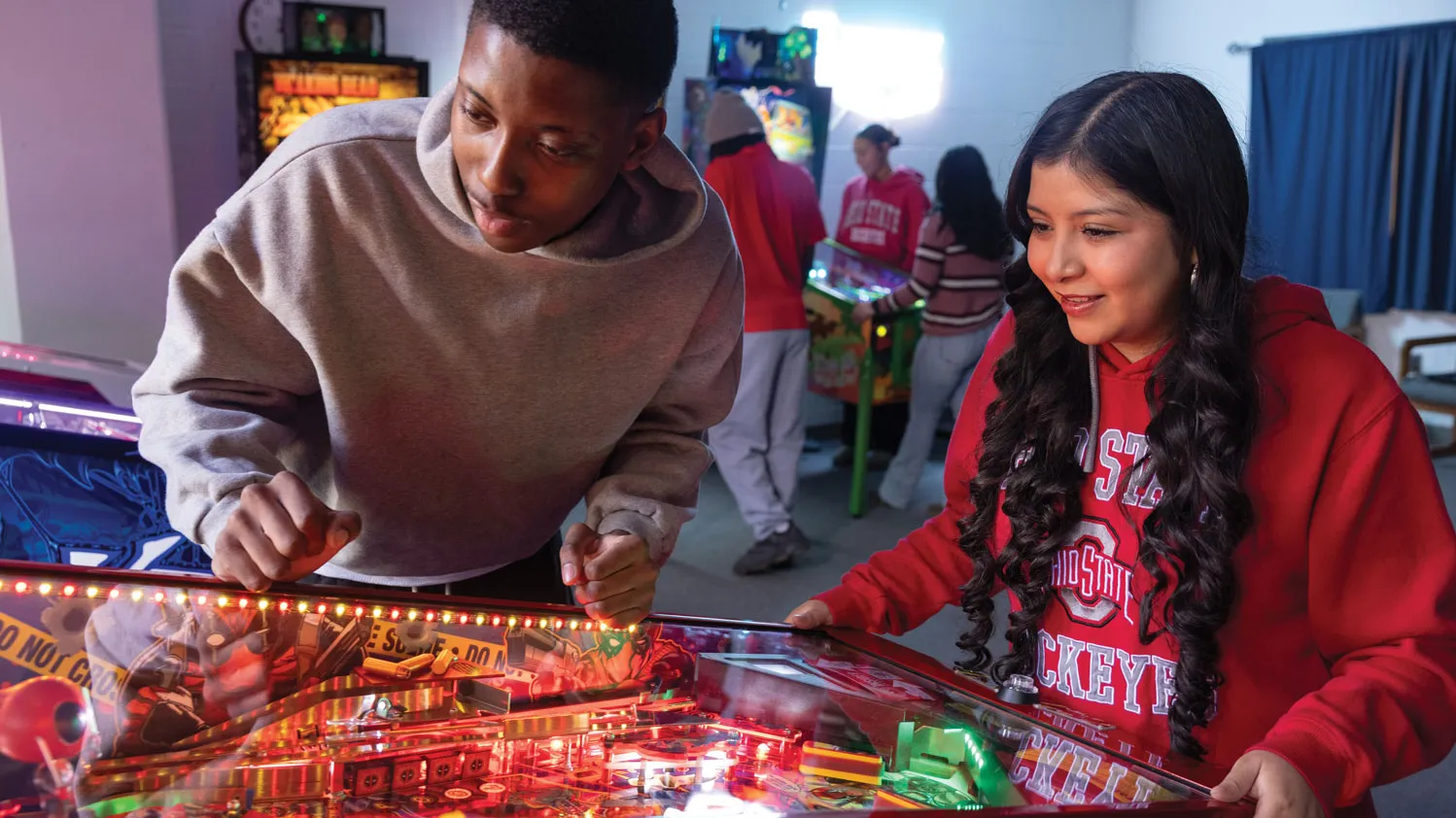 A pair of students have fun playing pinball at the Electric Playground.