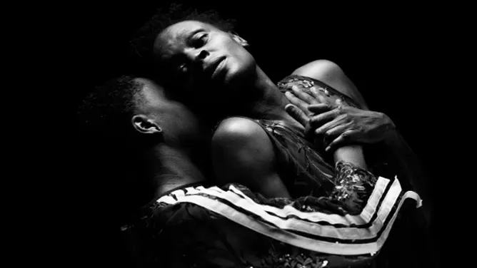 Two dancers hold each other in a dramatic black and white photo. 