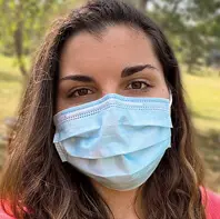 Woman wearing a blue surgical mask with long brown hair
