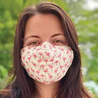 Woman with long brown hair wearing a cloth facemask with a flamingo pattern