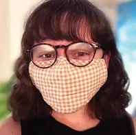 White woman with shoulder length brown hair and glasses wearing a cloth mask