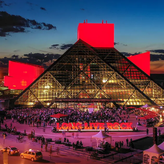 red and pink lights light up the rock and roll hall of fame at dusk