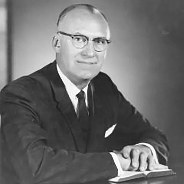 Novice Fawcett was a balding man posing in a suit with his hands on a book.