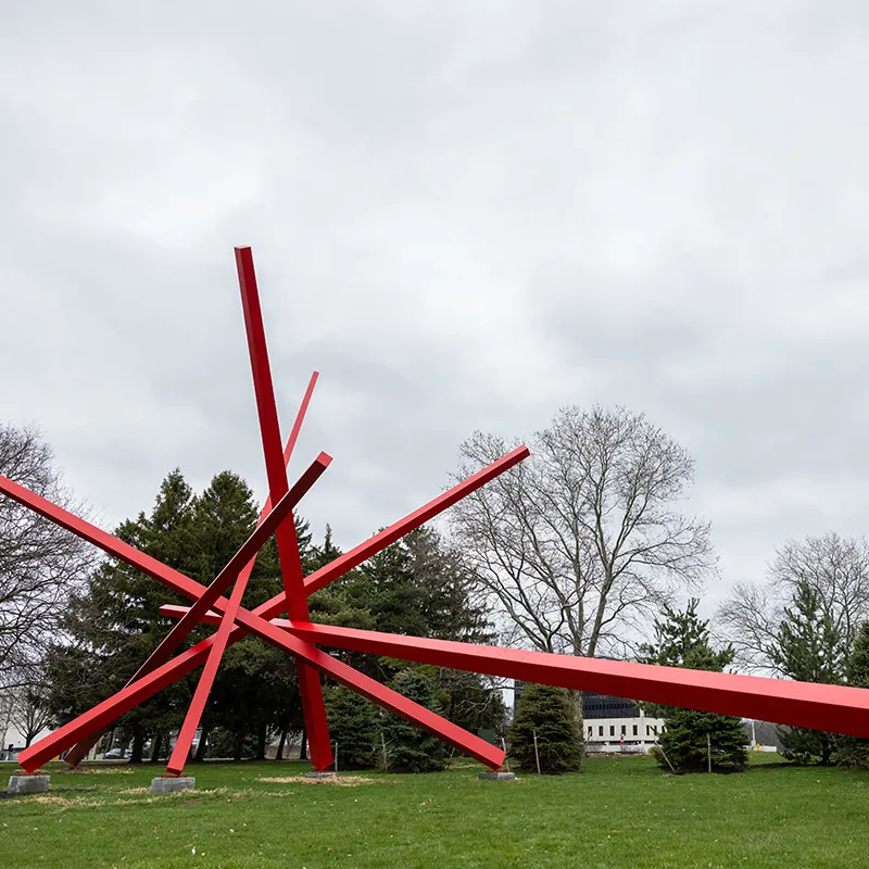A red starburst sculpture has one very long length extending. This sculpture is at least 25 feet long.