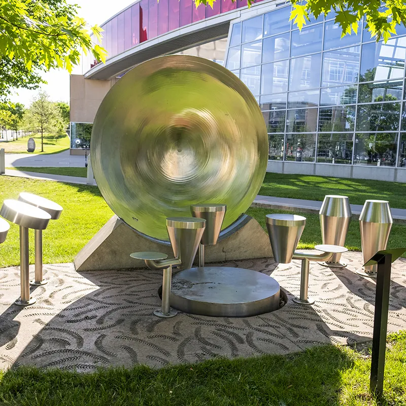 A huge metal gong-type instruments stands between smaller types of drums