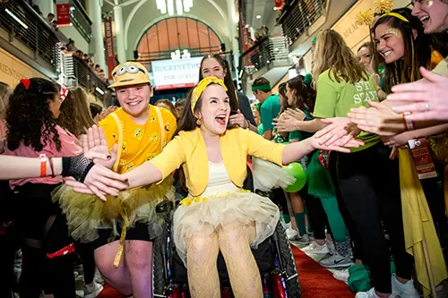 girl and boy in yellow running down aisle of people giving high fives