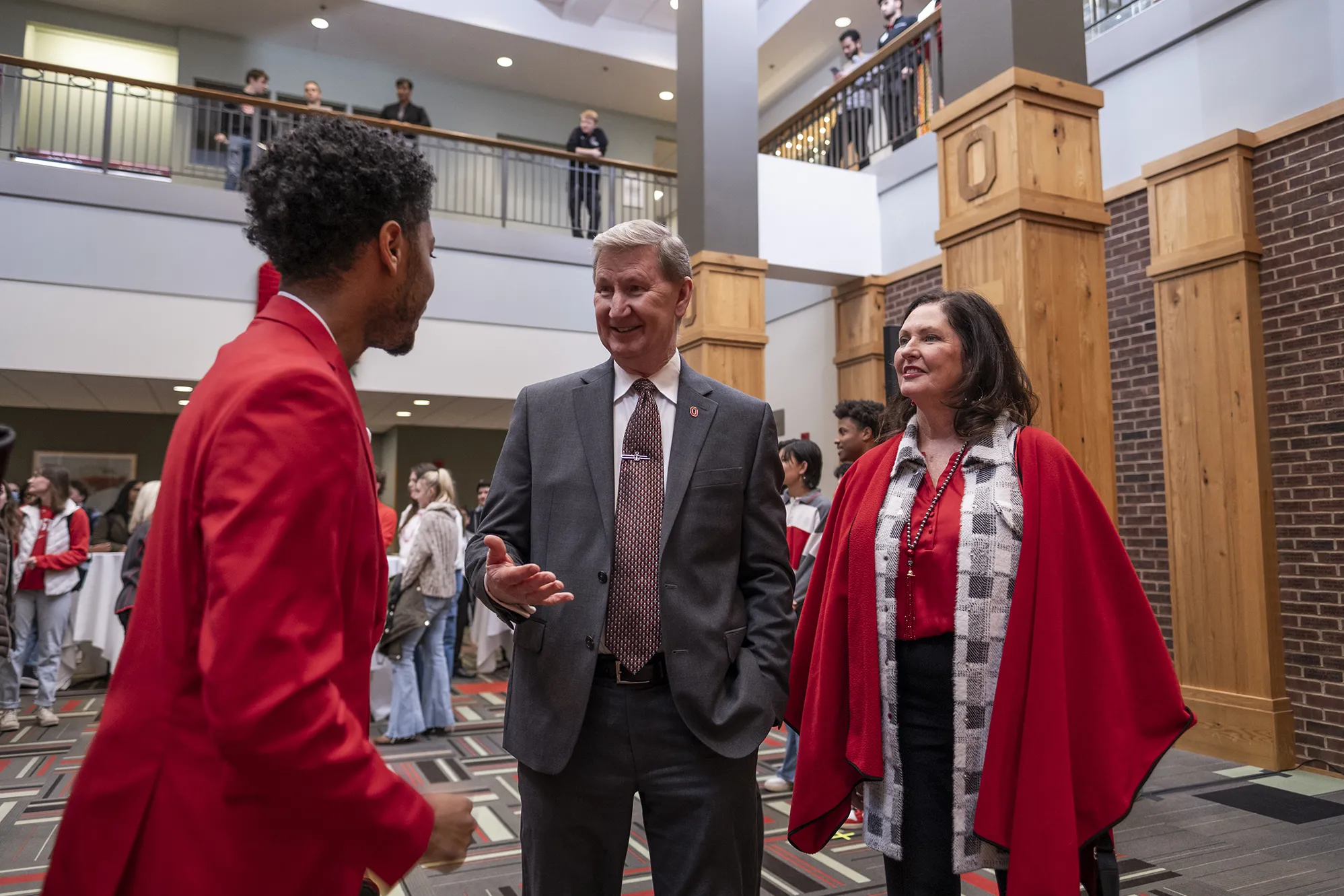 President Carter and his wife, Lynda, speak with Bobby McAlpine, president of the Undergraduate Student Government, at a student welcome reception in the Union. President Carter’s expression shows he is enjoying the conversation, and both he and his wife are paying close attention to McAlpine. They are all dressed well and other students mill in the background.