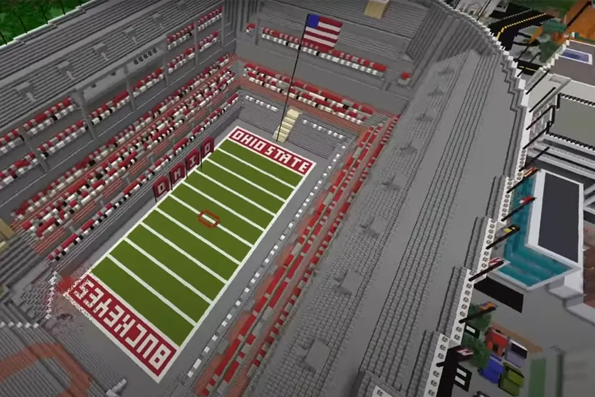 An aerial view of Messina's minecraft stadium, showing lines on the green turf and a crowd around the fiels