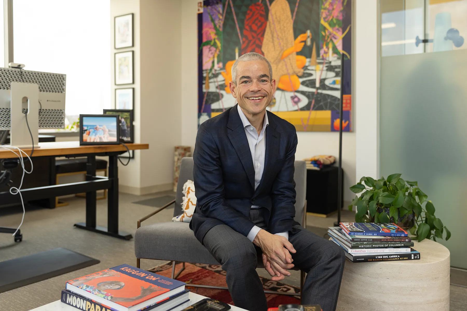 Matt Scantland smiles as he poses for a portrait in his office. He's a thin, white, middle age man with close cropped hair wearing a sportcoat. His smile is genuine.