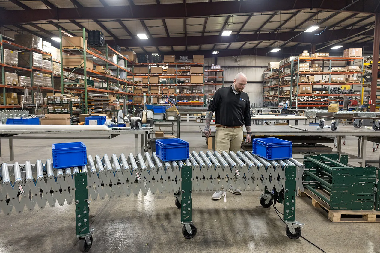 Zack stands along a conyer system he built, watching bright boxes move along to ensure it's working smoothly.